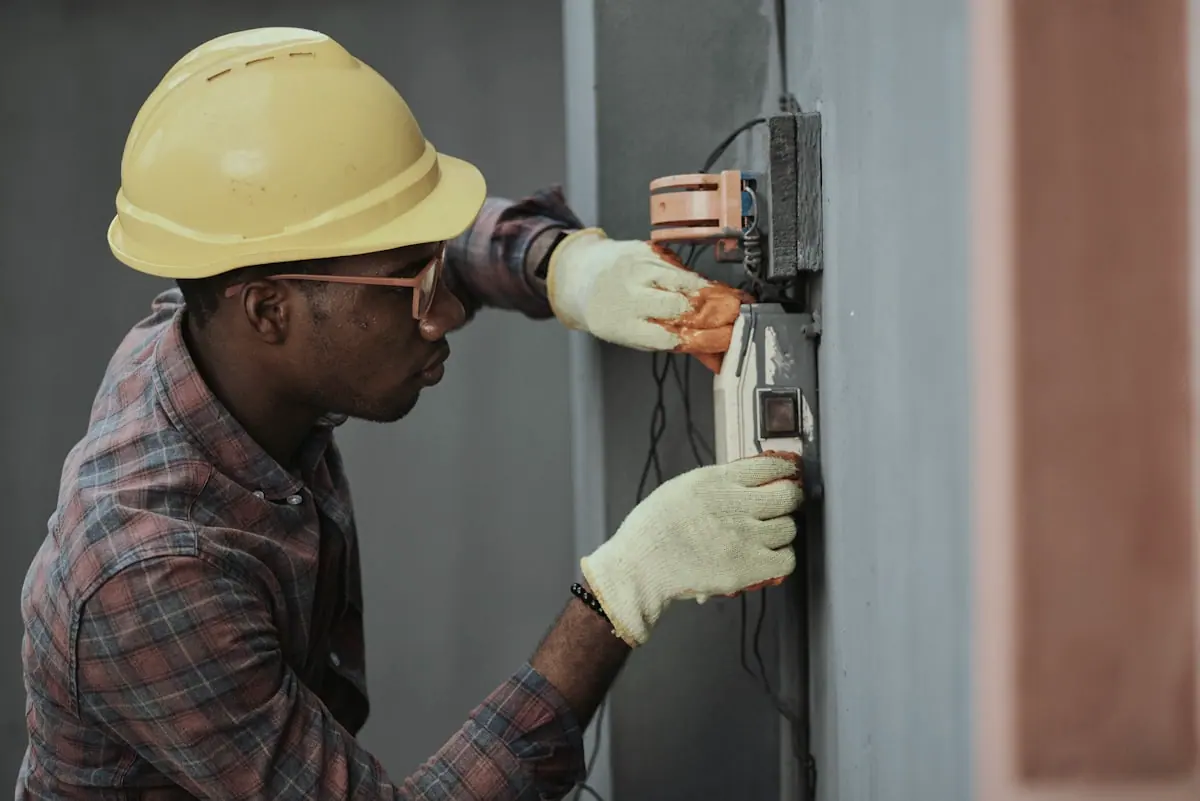 Electrician testing a wall-mounted electrical connection with a multimeter